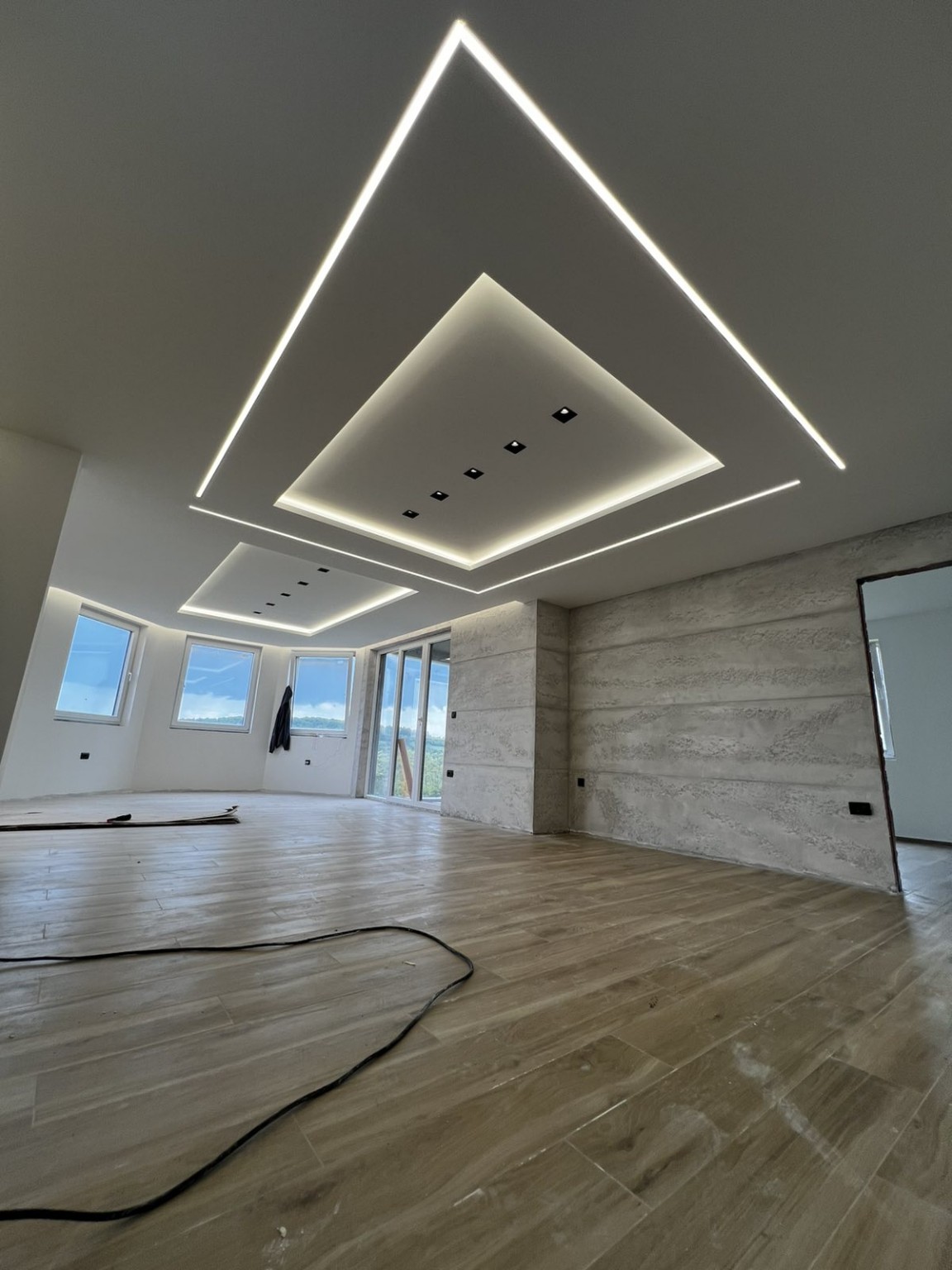 Spušteni plafon sa geometrijskom LED rasvetom i dekorativnim zidom